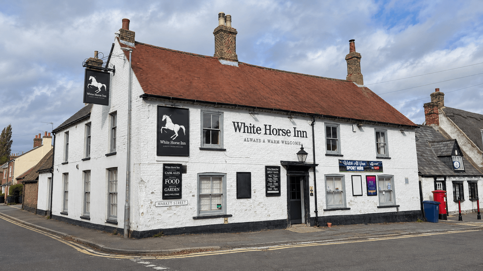 The White Horse Inn on the corner of Market Street, Swavesey, with white brickwork, a red tiled roof and hanging pub sign.