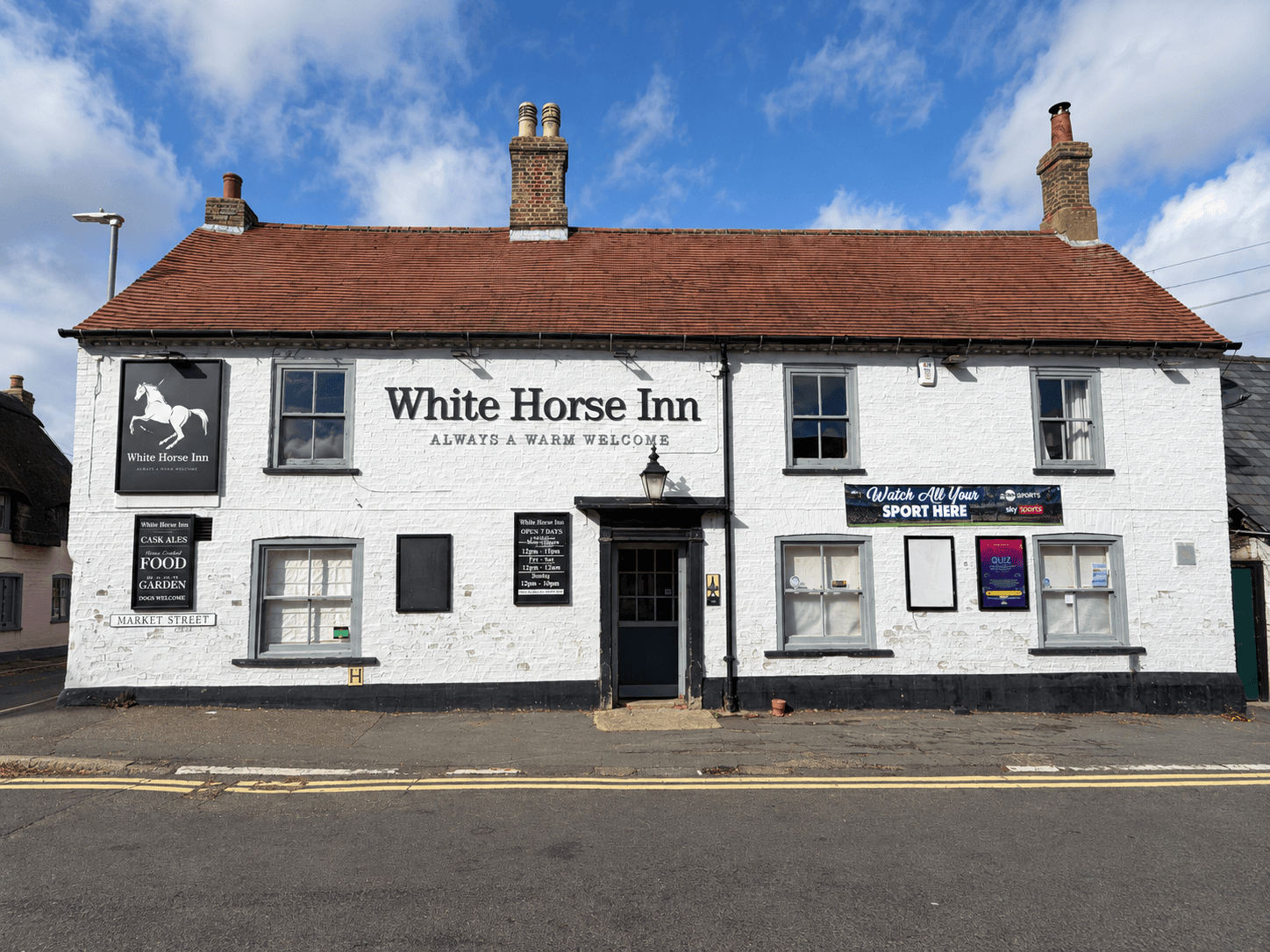 Front view of The White Horse Inn in Swavesey, with its pub sign, white brickwork and Market Street entrance.